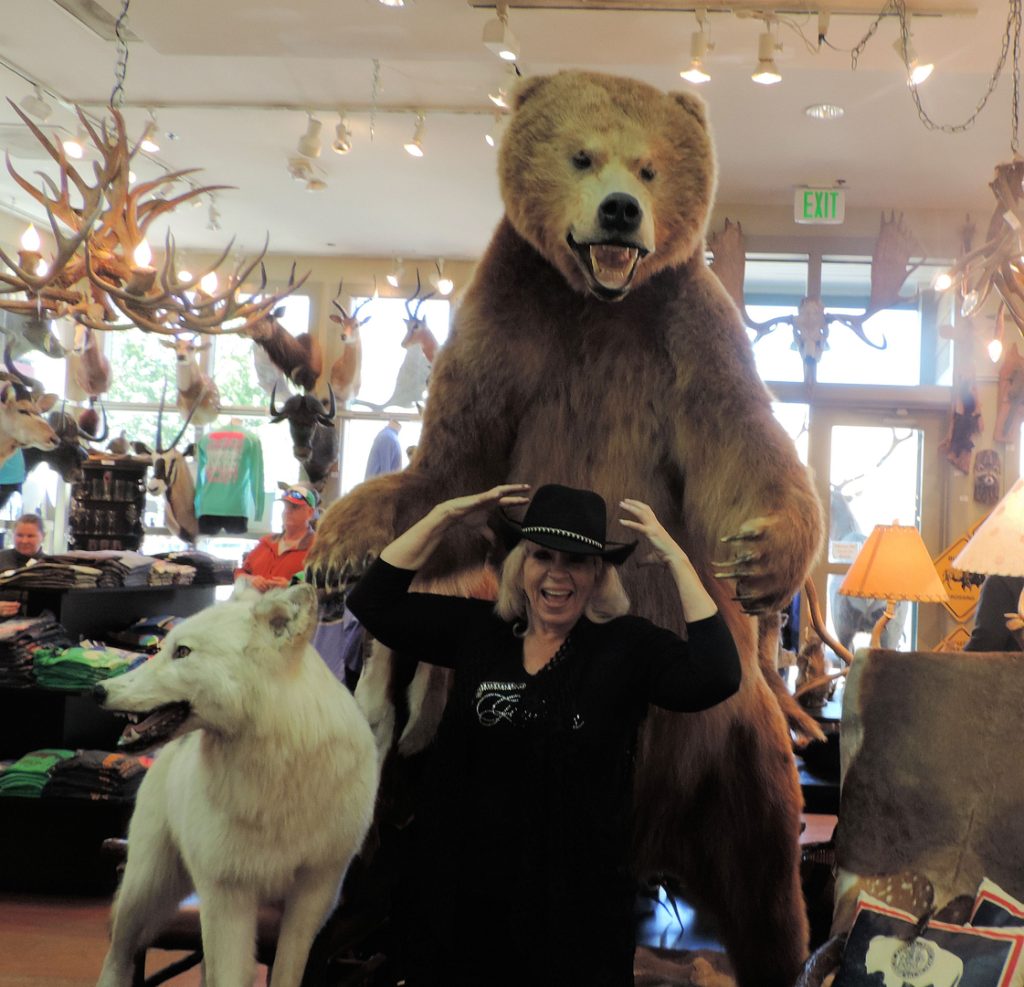 A woman standing next to a stuffed bear and two dogs.