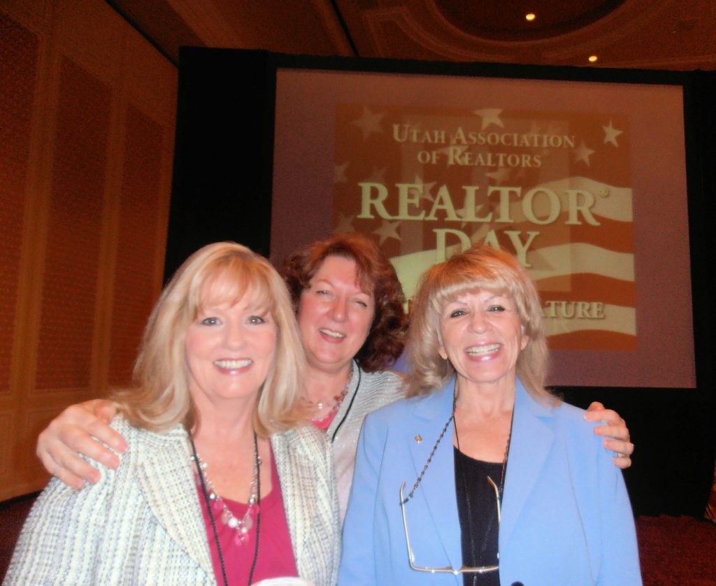 Three women are posing for a picture in front of a sign.