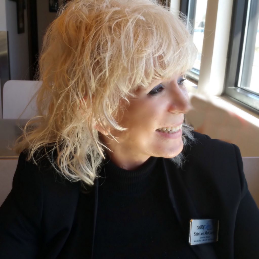 A woman with blonde hair sitting in front of a window.