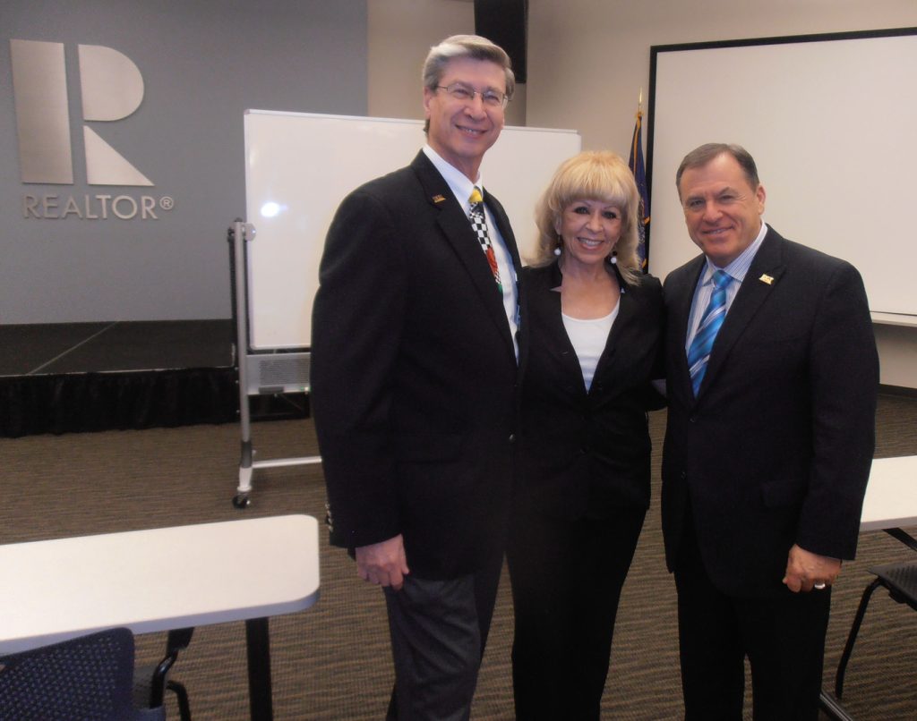 Three people in suits posing for a picture.