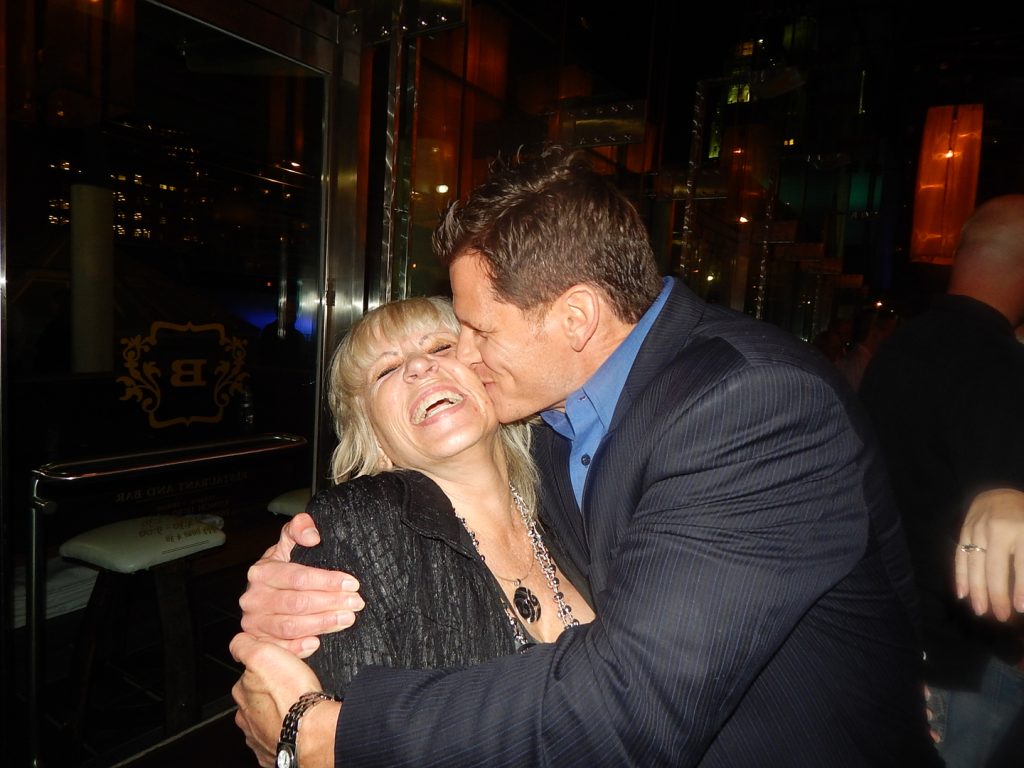 A man and woman kissing in front of a building.