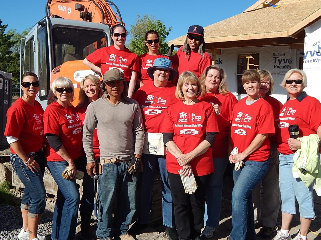 A group of people in red shirts standing next to a construction truck.