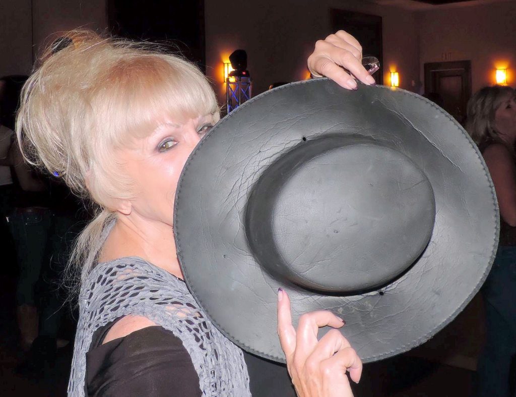 A woman holding onto a hat with her mouth.